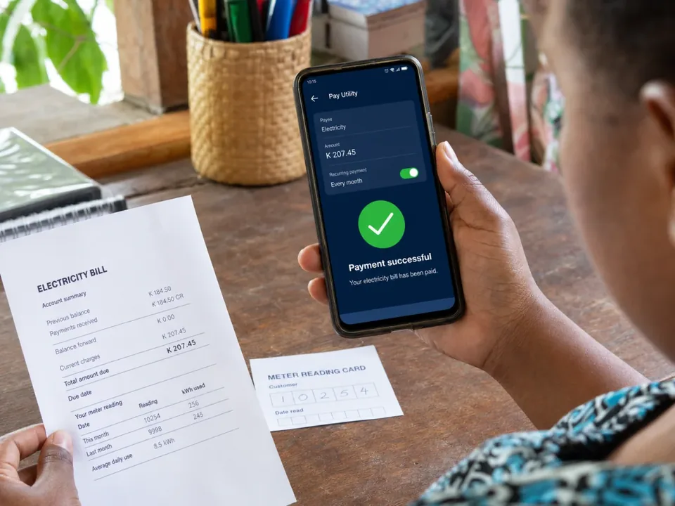 Person holding an electricity bill and a phone showing payment successful